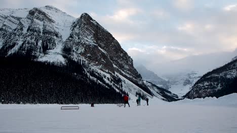 Jugando-Al-Hockey-En-Un-Lago-Congelado-Con-Montañas-De-Fondo