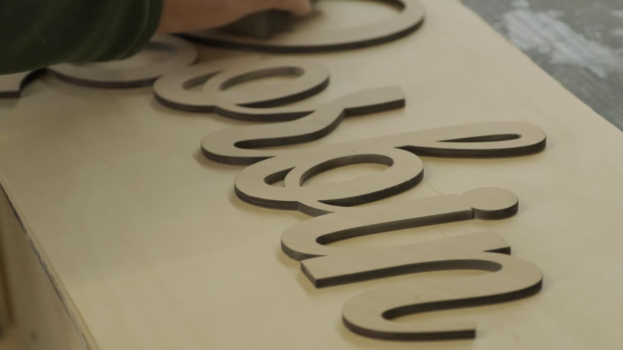 un carpintero está moliendo una pieza de madera, un producto de madera contrachapada hecho en una máquina láser cnc usando papel de arena