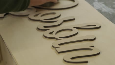 a carpenter is grinding a piece of wood, a plywood product made on a cnc laser machine using sandpaper