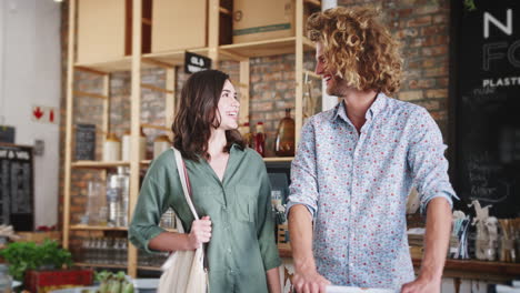 retrato de una pareja joven comprando en una tienda de comestibles sostenible sin plástico