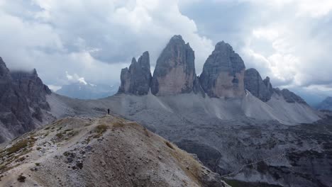 A-man-are-standing-alone-on-a-mountain-top-overlooking-Tre-Cime-di-Lavaredo,-also-known-as-Drei-Zinnen,-located-in-the-Dolomites-in-South-Tyrol-in-Italy