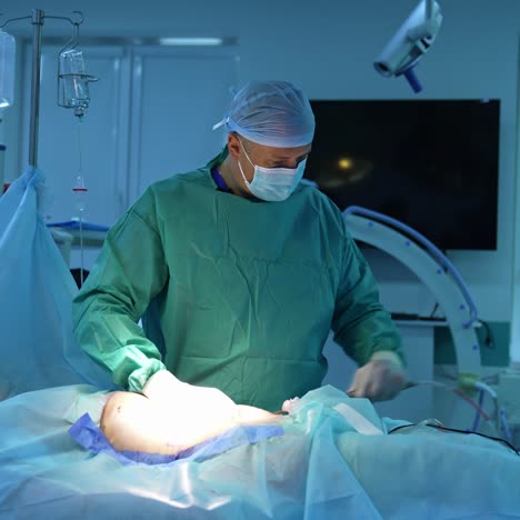 surgeon doing liposuction procedure for a patient. removal of the unwanted body fat by the medical specialist. doctor in protective uniform in a well-equipped surgery room
