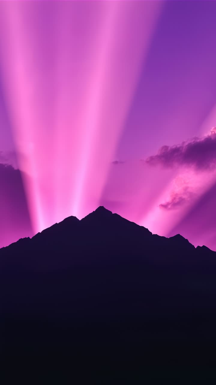 Video verticale: sagoma di cresta all'alba che emette raggi magenta sull'orizzonte, illuminando le nuvole