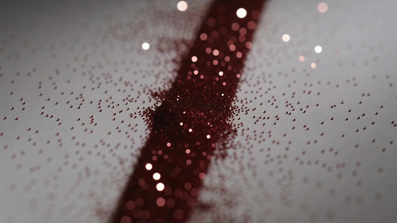 Il movimento della telecamera rivela una linea di glitter rossi su un lenzuolo chiaro, creando un effetto bokeh e mostrando granelli sparsi