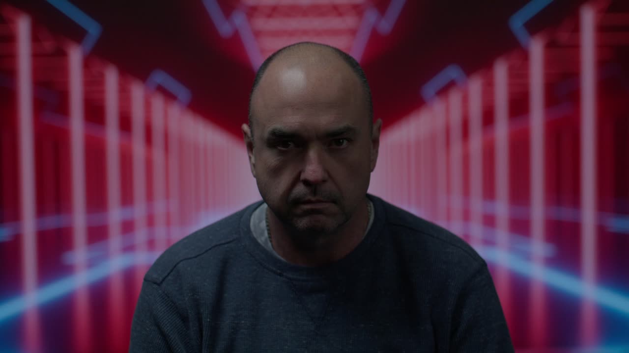 hombre blanco de mediana edad mirando a la cámara con una mirada en blanco con un fondo colorido en movimiento