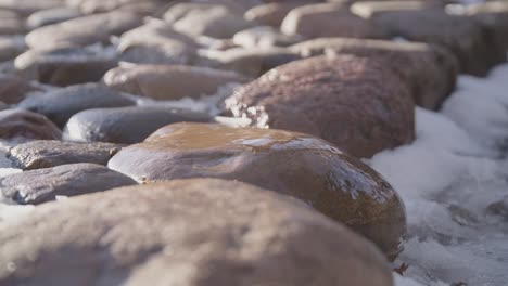 50-Fps-Wassertropfen,-Die-Auf-Granitstein-Fallen,-Wobei-Helles-Licht-Auf-Den-Steinweg-Fällt