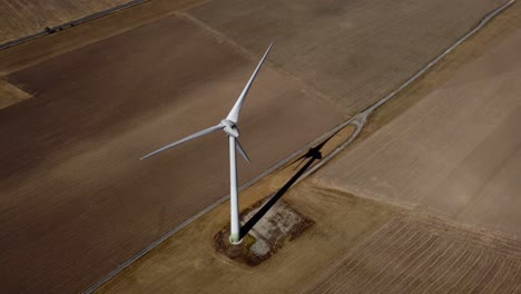 Toma-De-órbita-Aérea-De-Un-Solo-Aerogenerador-Girando-En-El-Viento,-Mediodía