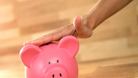 woman putting coin in piggy bank