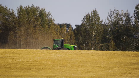 tractor working on the wheat field in red deer county, alberta, canada - wide shot