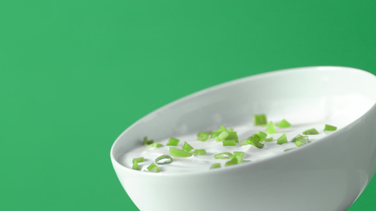 Bowl with sour cream and green onions slowly rotates.