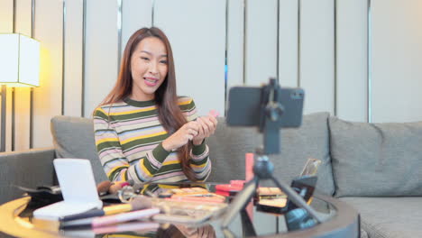 Asian-Beauty-blogger-applies-skin-powder-with-a-brush-while-filming-herself-on-a-smartphone-camera