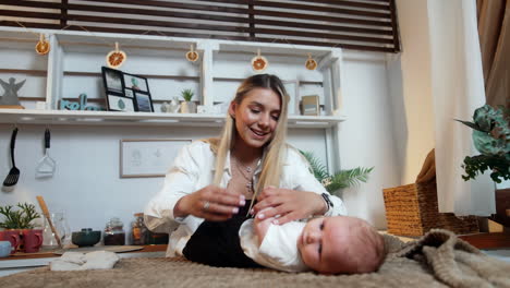 beautiful smiling blonde woman putting on pants on her newborn boy. mommy changing clothes to a baby. low angle view.