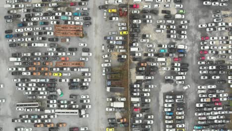 vista aérea hacia abajo vista sobre estacionamientos al aire libre con muchos vehículos de tipo y color aleatorios.