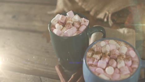 animation of light trails over mugs with cocoa on wooden background