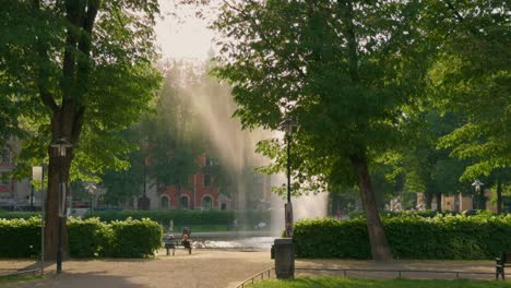 people relax by fountain at city square karlaplan in stockholm in afternoon sun