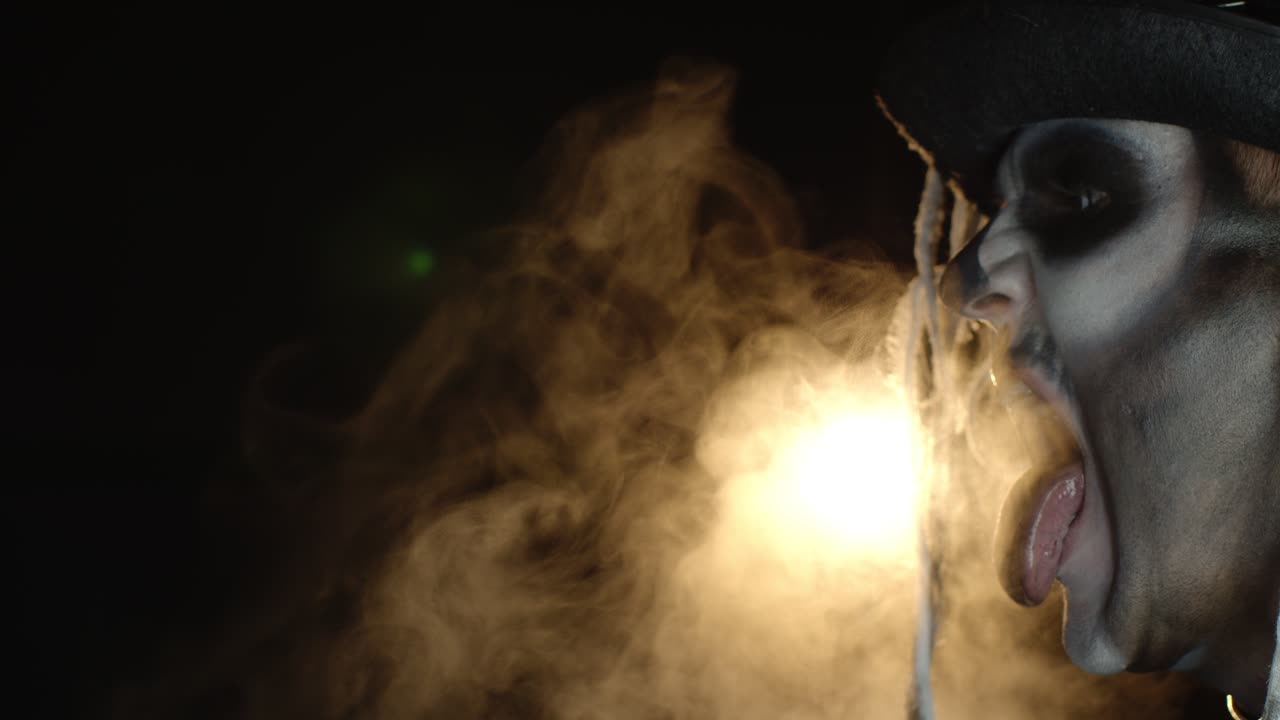 hombre espeluznante con maquillaje de esqueleto haciendo caras, abriendo la boca tratando de comer luz, mostrando la lengua