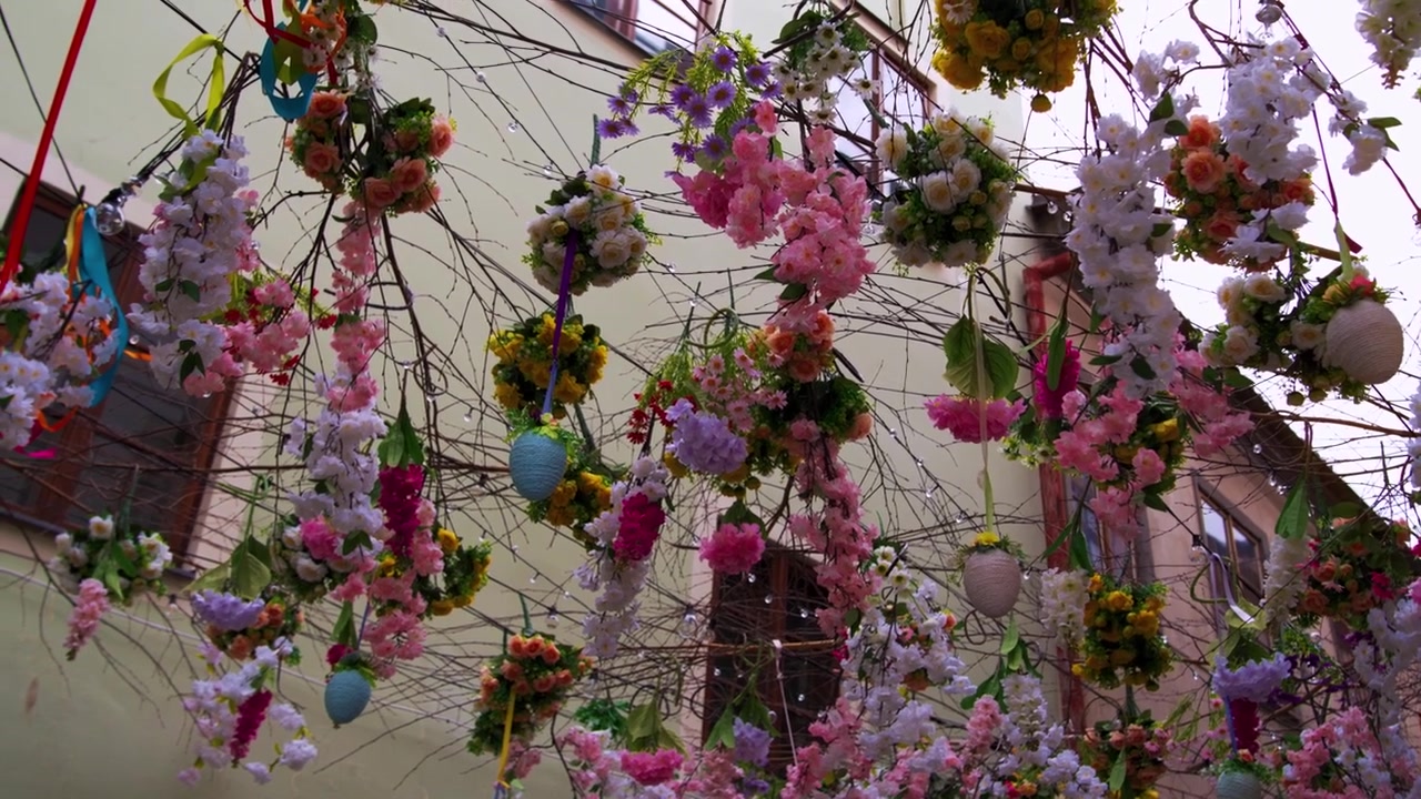 Pink and white spring flowers with Easter eggs decorating narrow Czech old town street, slow motion