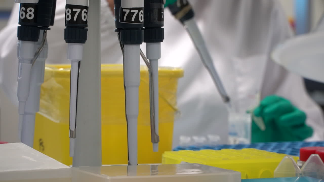 Research scientist works with green gloves in lab, blurry background, static