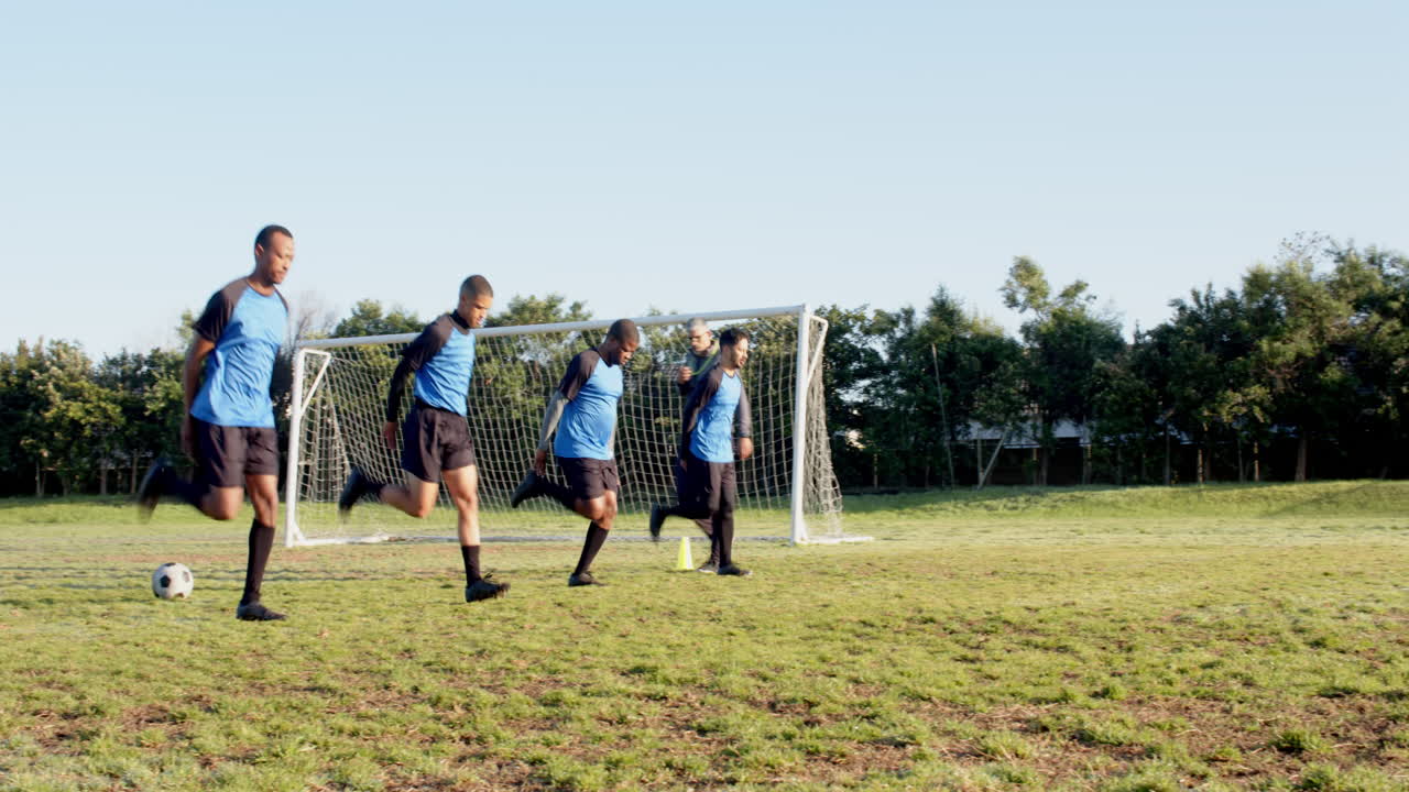 Playing soccer, group of boys running towards goal on grassy field