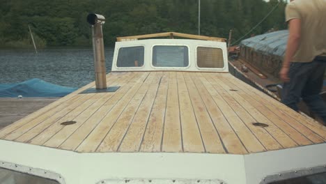 carpenter walking along deck of wooden boat repair project