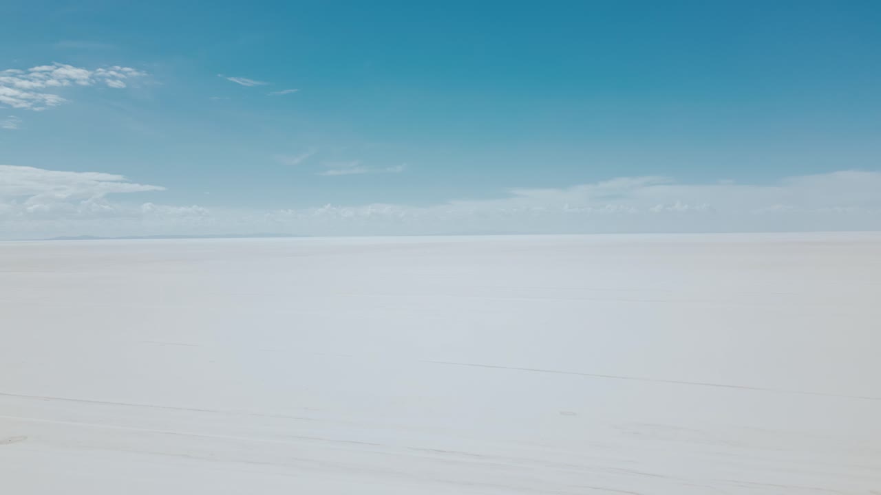 Explore the surreal beauty of Bolivia's Salar de Uyuni with stunning drone footage showcasing the vast expanse of the endless salt flats from an aerial view in daylight.