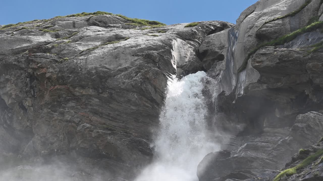 Waterfall in the swiss alps during a sunny day, cascade creates humidity and fog, Wallis