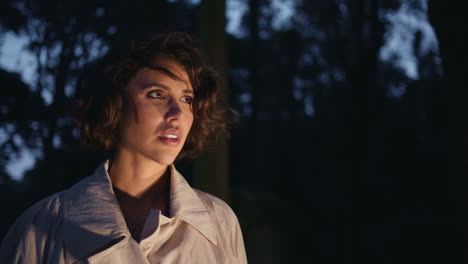 girl standing night forest illuminated by car headlights closeup. confused woman