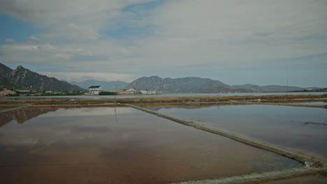panoramic view of salt flats with mountains and reflections under a cloudy sky