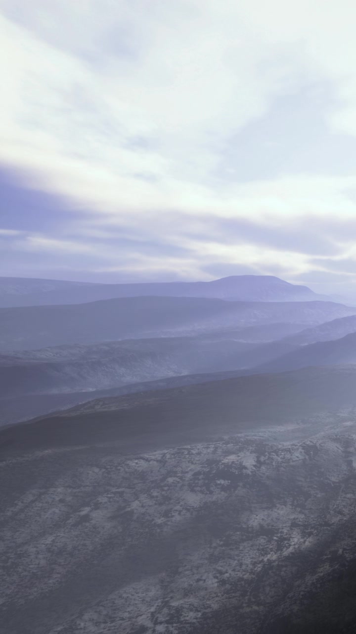 Fjell og daler danner fjerne lag under himmelen ved solnedgang