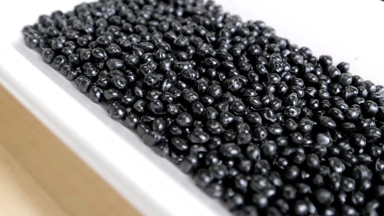 Black polymer granules in a garbage recycling plant. Raw materials for recycled plastic are used in manufacturing.