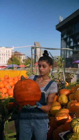 woman holding a pumpkin at a farmers market