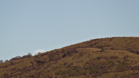 Lapso-De-Tiempo-De-La-Luna-Saliendo-Sobre-Una-Montaña-Durante-El-Día