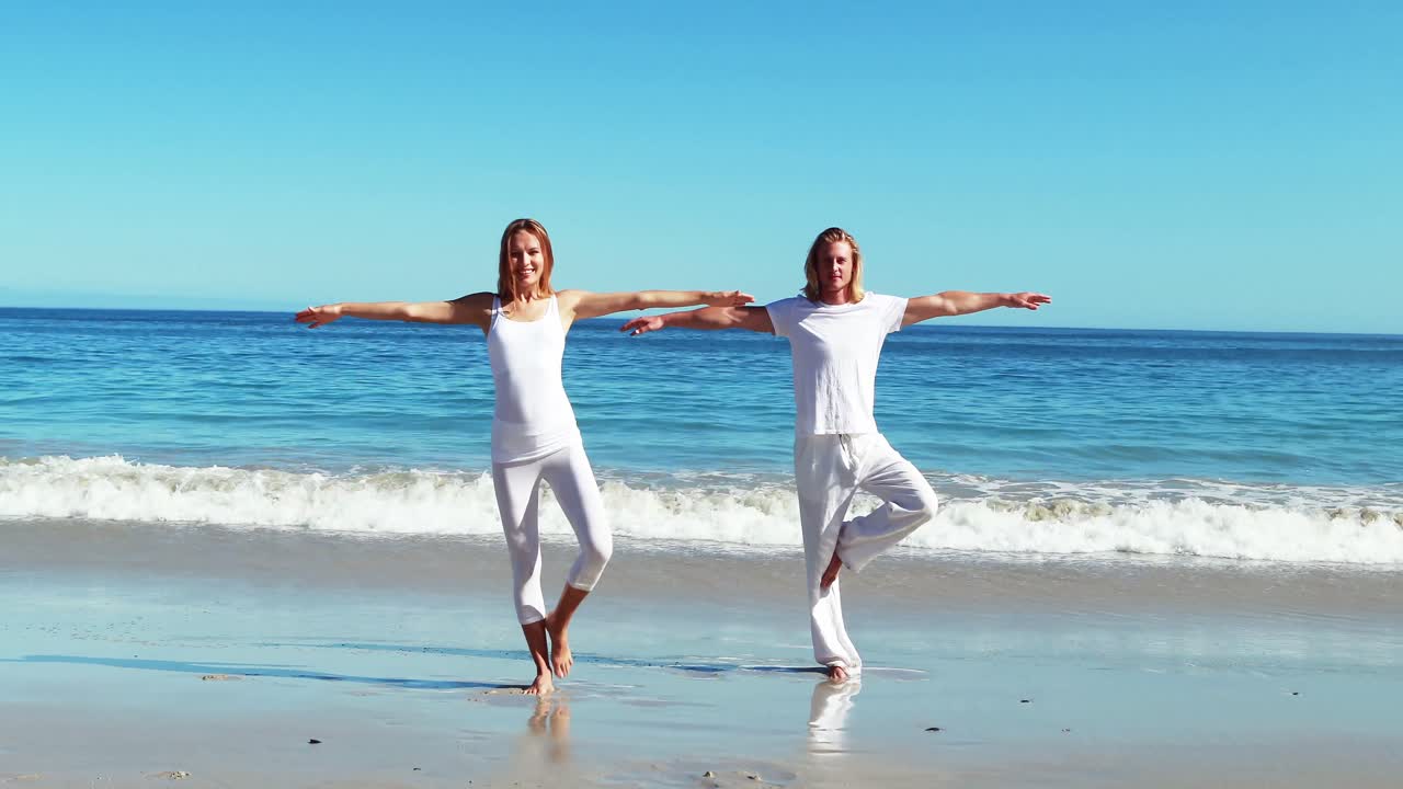 해변 에서 요가 를 하는 부부