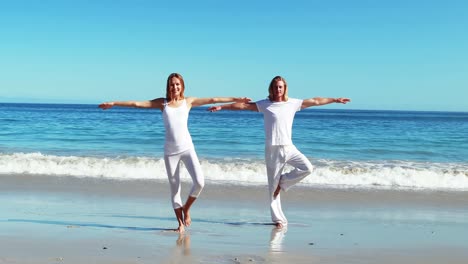 Couple-performing-yoga-at-beach