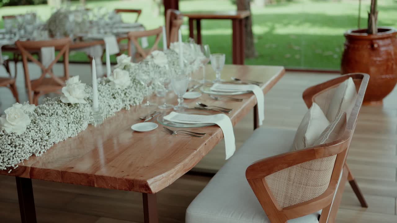Wooden wedding table set with white roses baby's breath and candles for intimate seating