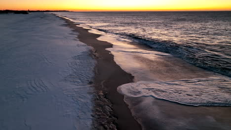 snow on shoreline waves break in ocean