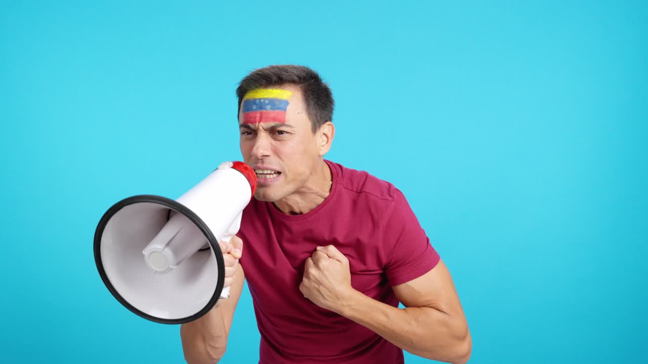 Excited man with venezuelan flag on face using a megaphone