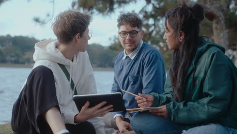 students using digital tablet and talking in the park