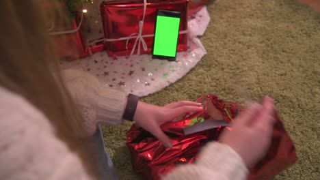 woman opens christmas gift during family video call