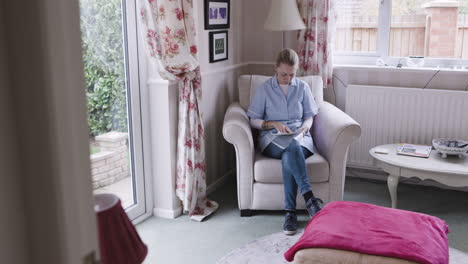 woman sitting in armchair reading