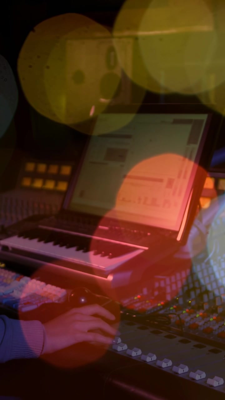 Video verticale: Artista donna che preme un tasto per avviare una DAW musicale, utilizzando tastiera MIDI e mixer con effetto bokeh