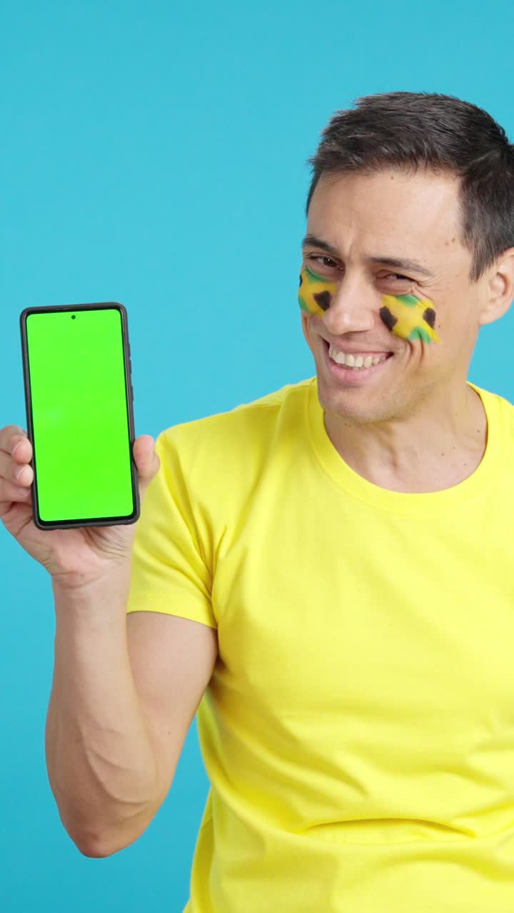 Jamaican supporter looking at his mobile smiling and showing it