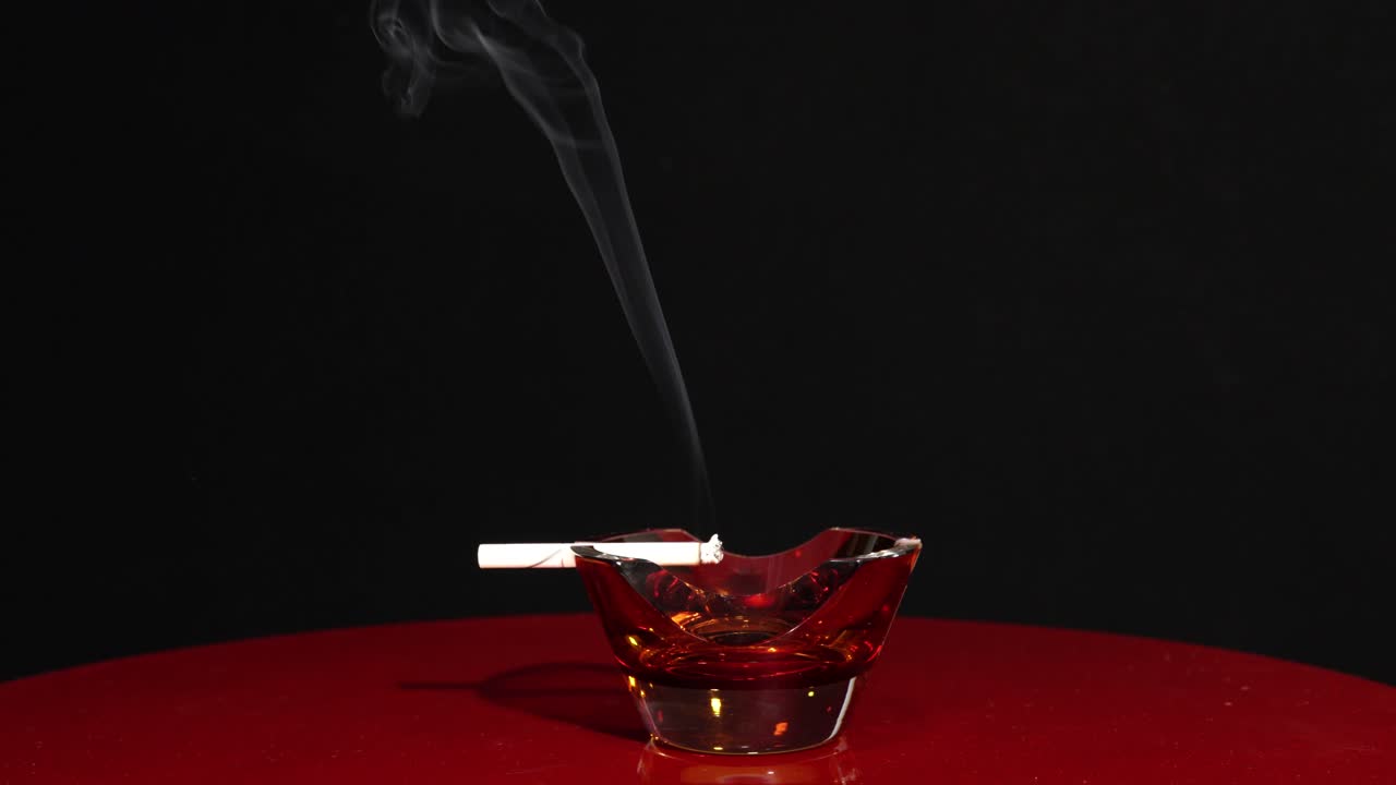 fumar cigarrillo aislado en fondo oscuro, arder en cenicero, dejar de fumar concepto