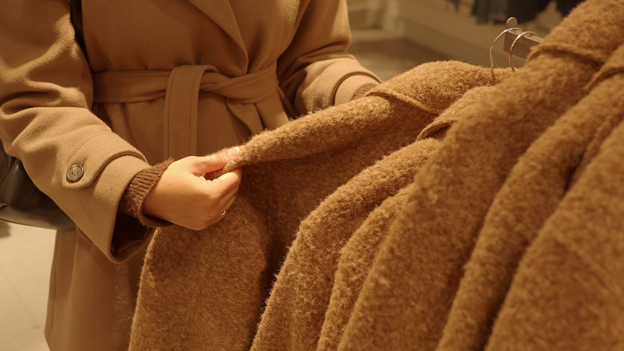 Woman's Hands Feeling Fabric of Brown Coat in Clothing Store