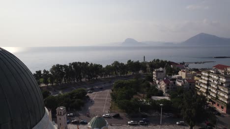 Aerial-pullback-from-Gulf-of-Patras-revealing-the-Dome-of-Orthodox-Saint-Andrew-Church,-Greece