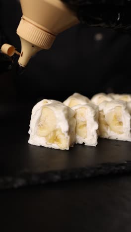 chef preparing delicious banana sushi with chocolate sauce