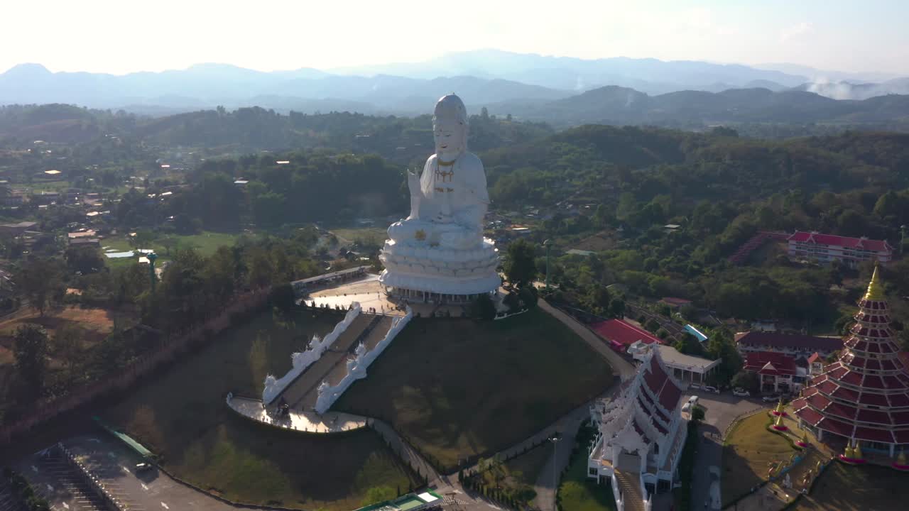 drone aéreo de wat huay pla kang enorme estatua blanca grande y templo de pagoda con montañas y espacio terrestre en chiang rai, tailandia