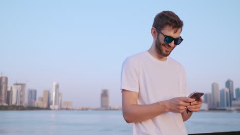 the man dials the number on the phone and talks on the background of the panorama of dubai. hand close-up