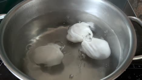 Chicken-eggs-cooking-in-a-stainless-steel-pan-with-hot-water-boiling-and-the-eggs-are-covered-with-many-small-air-bubbles