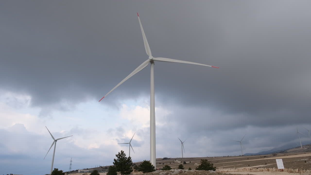 A large wind turbine plant. Sustainable and renewable green energy from the wind. Turbines arranged on a mountain plateau. Windy weather before the storm.